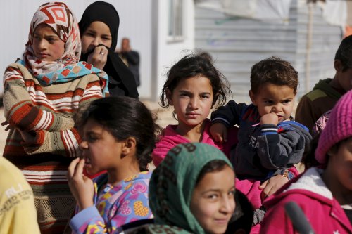 Syrian refugees watch as Britain's Foreign Secretary Philip Hammond visits Al Zaatari refugee camp in Mafraq, Jordan
